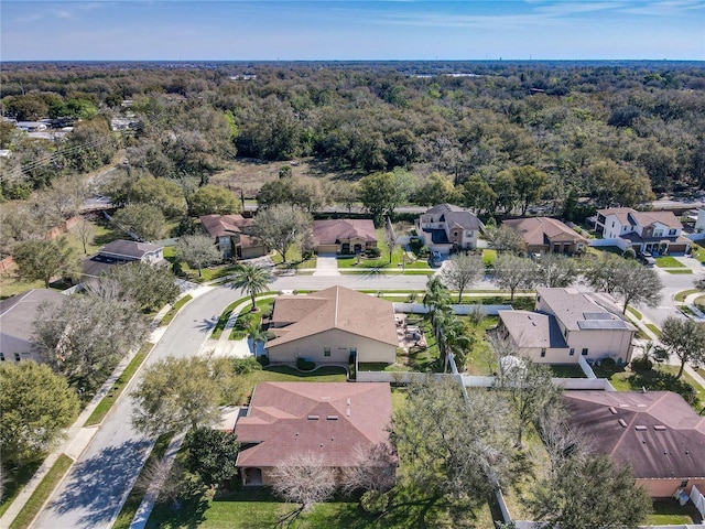 drone / aerial view featuring a wooded view and a residential view