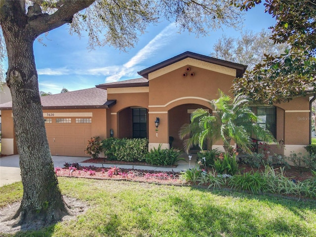 mediterranean / spanish house featuring roof with shingles, stucco siding, a garage, driveway, and a front lawn