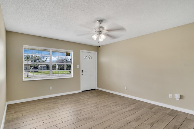 entryway featuring ceiling fan, a textured ceiling, baseboards, and wood finished floors