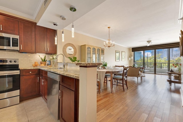 kitchen featuring a peninsula, ornamental molding, decorative backsplash, a sink, and appliances with stainless steel finishes