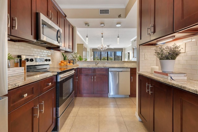 kitchen featuring a sink, appliances with stainless steel finishes, crown molding, light tile patterned floors, and hanging light fixtures