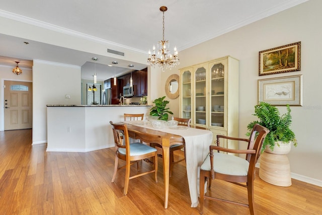 dining area featuring crown molding, light wood-style flooring, baseboards, and visible vents