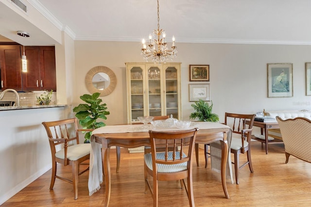 dining space featuring a notable chandelier, visible vents, light wood-style flooring, and ornamental molding