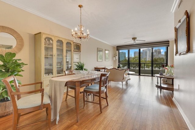 dining area featuring crown molding, baseboards, a city view, light wood-type flooring, and a ceiling fan