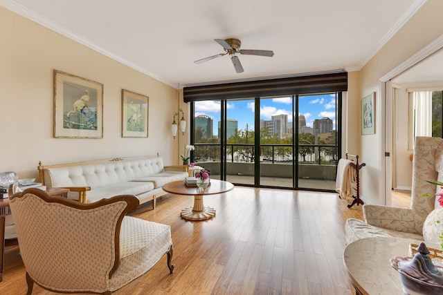 living area featuring a city view, ornamental molding, a ceiling fan, wood finished floors, and baseboards