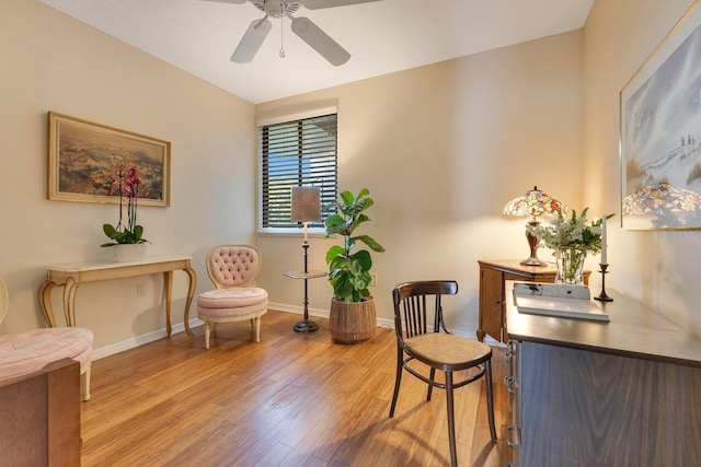 living area featuring baseboards, light wood-type flooring, and ceiling fan