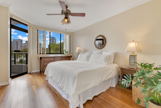 bedroom with a view of city, light wood-style flooring, ornamental molding, baseboards, and ceiling fan