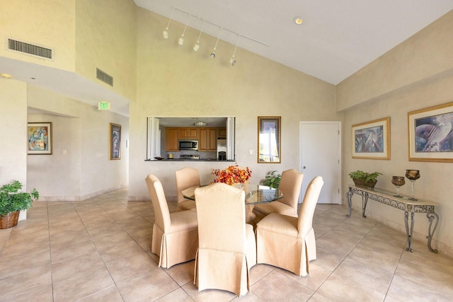 dining room with light tile patterned floors, visible vents, baseboards, and high vaulted ceiling