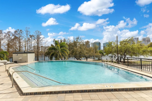 community pool featuring a patio area, a city view, and fence