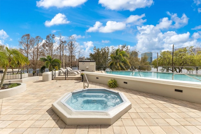 community pool with an outdoor structure, a patio area, fence, and a hot tub