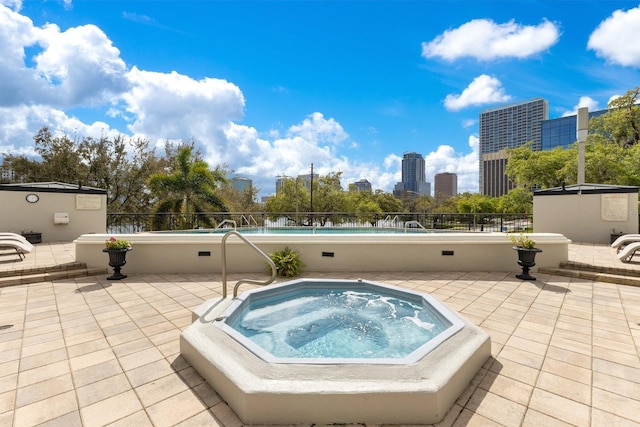 view of pool featuring a patio, a view of city, and a community hot tub