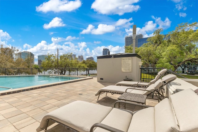 community pool with a city view, a patio, and outdoor lounge area