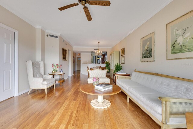 living area with light wood-type flooring, visible vents, ornamental molding, and ceiling fan with notable chandelier