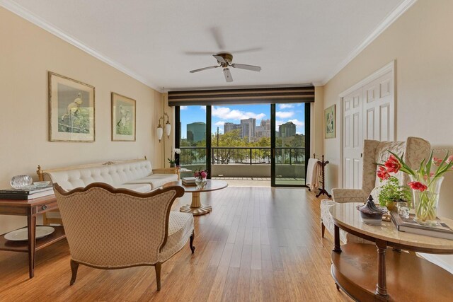 living room featuring wood finished floors, a view of city, ornamental molding, and a ceiling fan