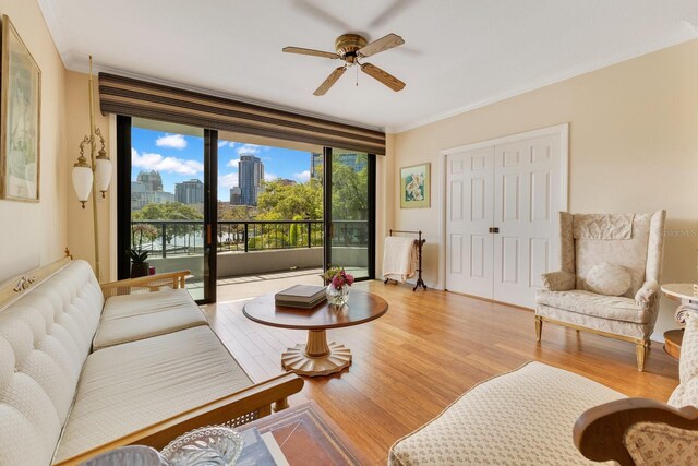 living area with a view of city, a ceiling fan, crown molding, and light wood finished floors