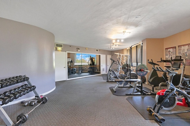 exercise room with visible vents, baseboards, and a textured ceiling