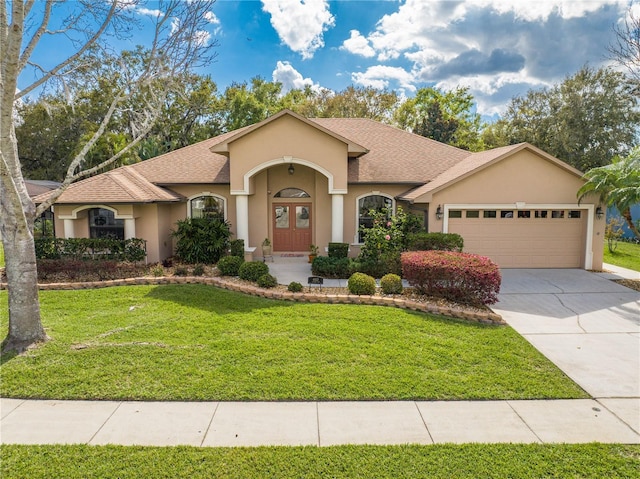 view of front of home with a front lawn, a garage, and stucco siding