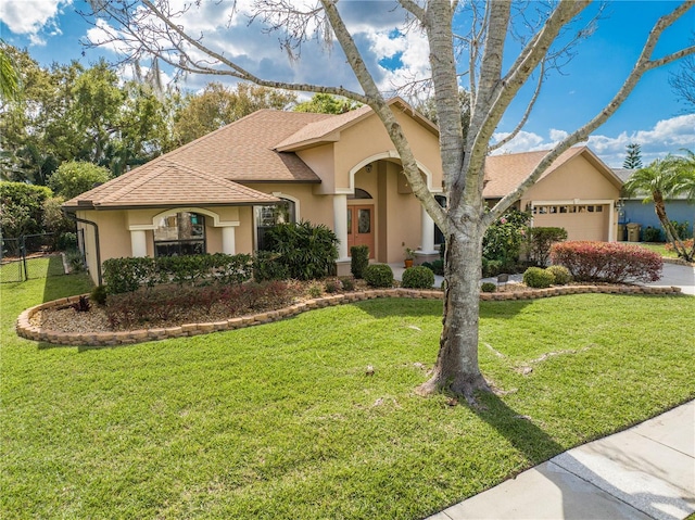 mediterranean / spanish home with stucco siding, a front yard, a garage, and roof with shingles