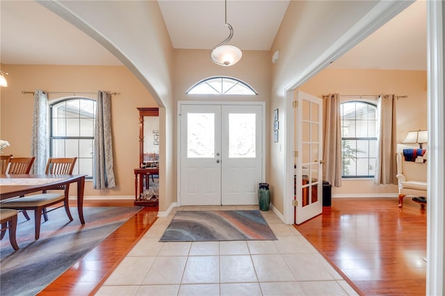 entryway featuring light wood finished floors, french doors, baseboards, and arched walkways