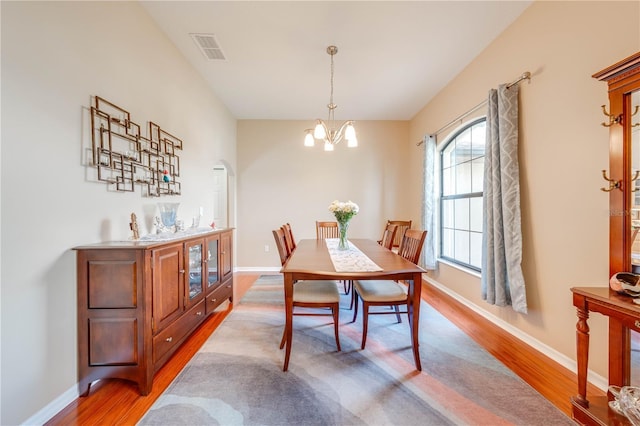 dining space featuring a chandelier, visible vents, baseboards, and wood finished floors