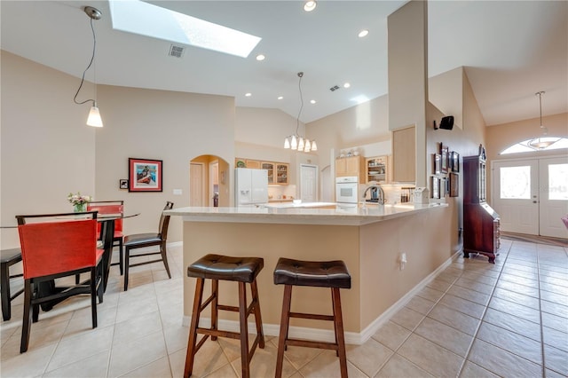 kitchen featuring arched walkways, a peninsula, light tile patterned flooring, and white fridge with ice dispenser