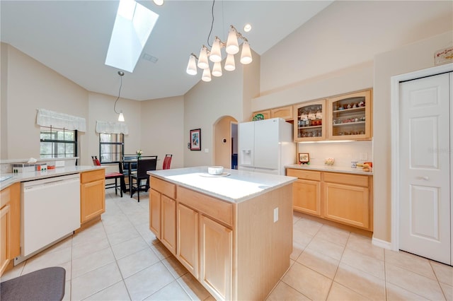 kitchen with white appliances, light tile patterned floors, light brown cabinets, and arched walkways