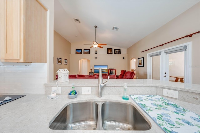 kitchen with visible vents, light brown cabinetry, open floor plan, lofted ceiling, and a sink