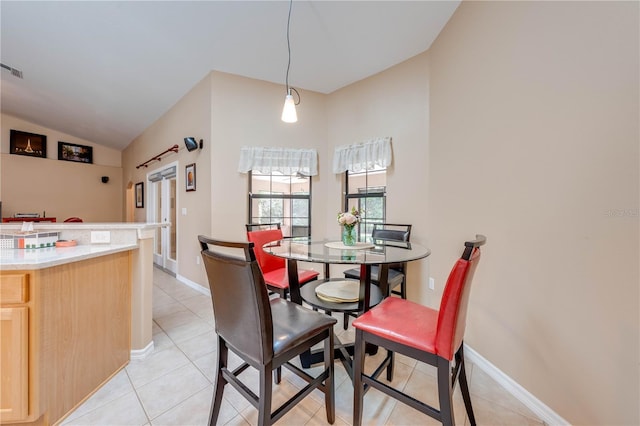 dining room featuring light tile patterned floors, baseboards, and vaulted ceiling