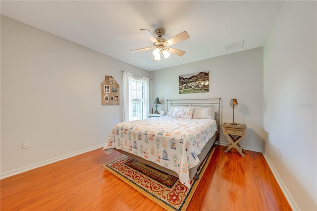 bedroom featuring visible vents, baseboards, wood finished floors, and a ceiling fan