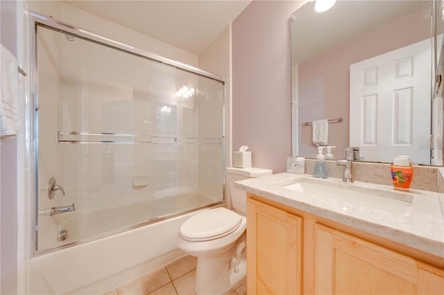 bathroom with tile patterned floors, combined bath / shower with glass door, toilet, and vanity