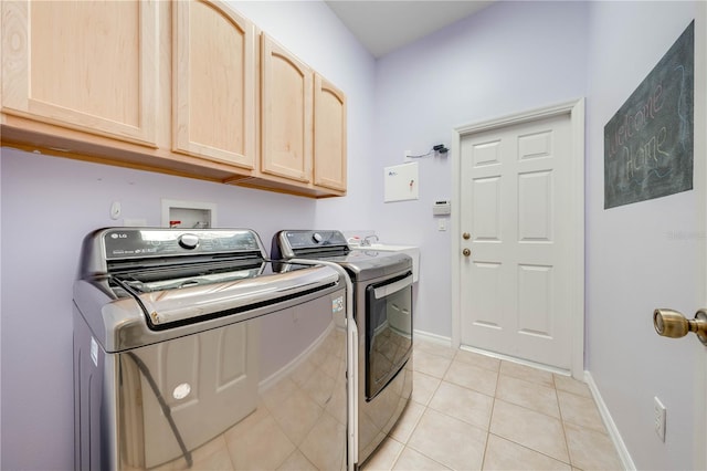 laundry area featuring light tile patterned floors, baseboards, cabinet space, and washing machine and dryer