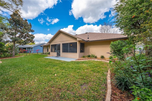 rear view of property with a yard, a patio, fence, and stucco siding