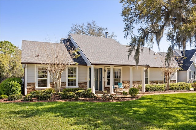 view of front facade with brick siding, roof with shingles, and a front yard