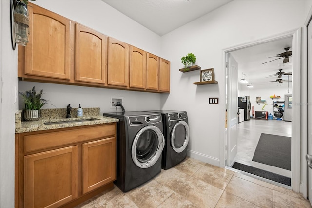 washroom with cabinet space, ceiling fan, a sink, separate washer and dryer, and baseboards