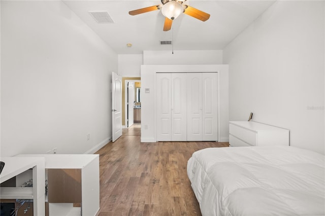 bedroom with a closet, visible vents, baseboards, and wood finished floors