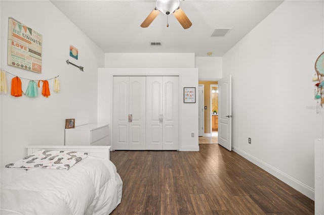 bedroom with a closet, dark wood-style flooring, visible vents, and baseboards