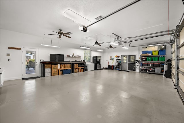 garage featuring a garage door opener, stainless steel fridge, visible vents, and a ceiling fan