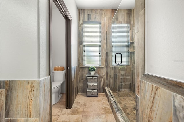 bathroom featuring toilet, a shower stall, and tile patterned flooring