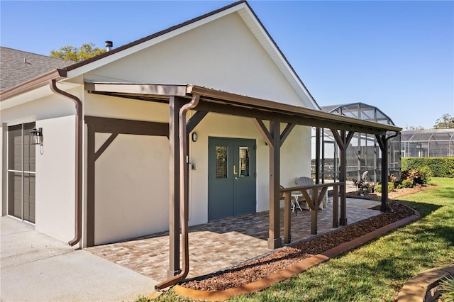 exterior space featuring a patio area, roof with shingles, glass enclosure, and stucco siding