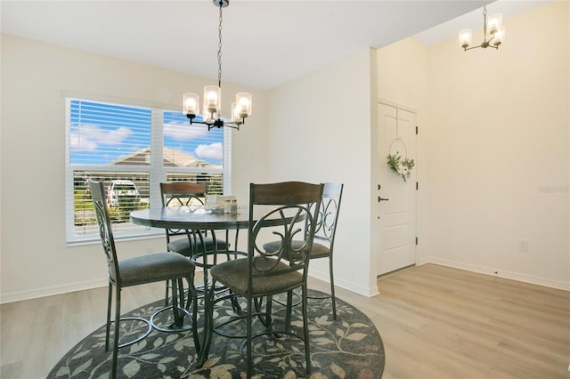 dining space with baseboards, a chandelier, and light wood finished floors