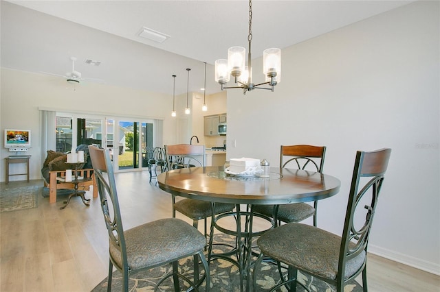 dining area featuring a notable chandelier, visible vents, baseboards, and light wood-style floors