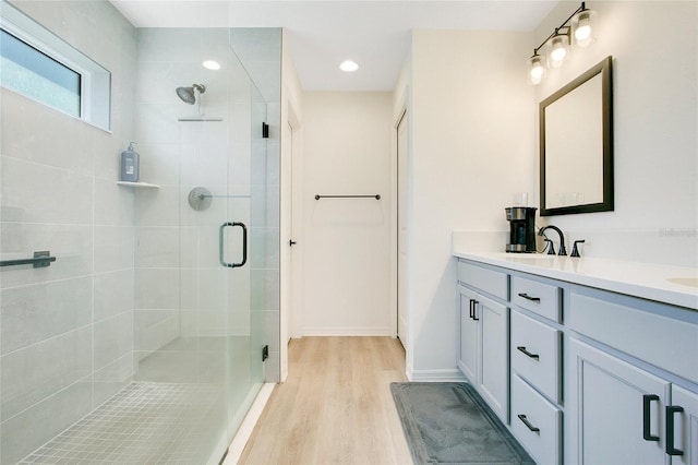 bathroom featuring a shower stall, vanity, baseboards, and wood finished floors