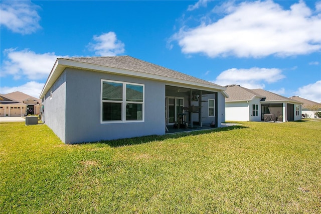 rear view of property featuring central AC unit, stucco siding, a yard, and a sunroom