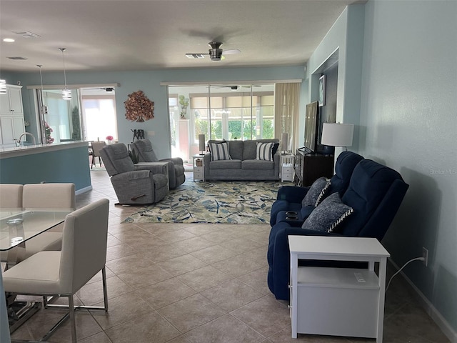 tiled living area featuring a sink, visible vents, baseboards, and a ceiling fan