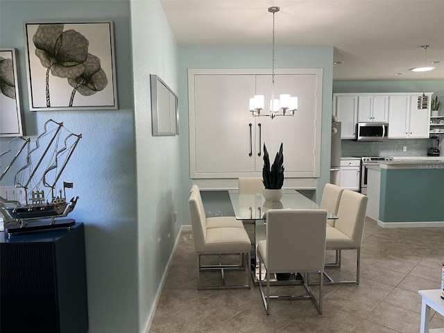 dining area featuring light tile patterned flooring, a notable chandelier, and baseboards