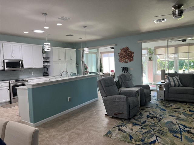 kitchen with visible vents, stainless steel appliances, light countertops, white cabinets, and open floor plan