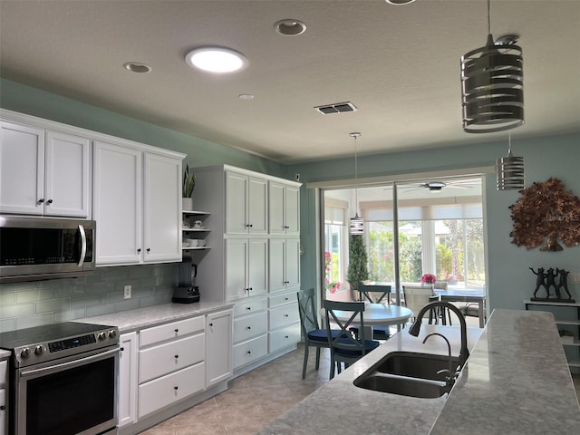 kitchen with a ceiling fan, a sink, open shelves, stainless steel appliances, and decorative backsplash