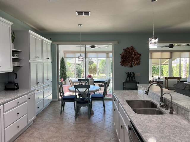 kitchen featuring visible vents, white cabinetry, a ceiling fan, and a sink