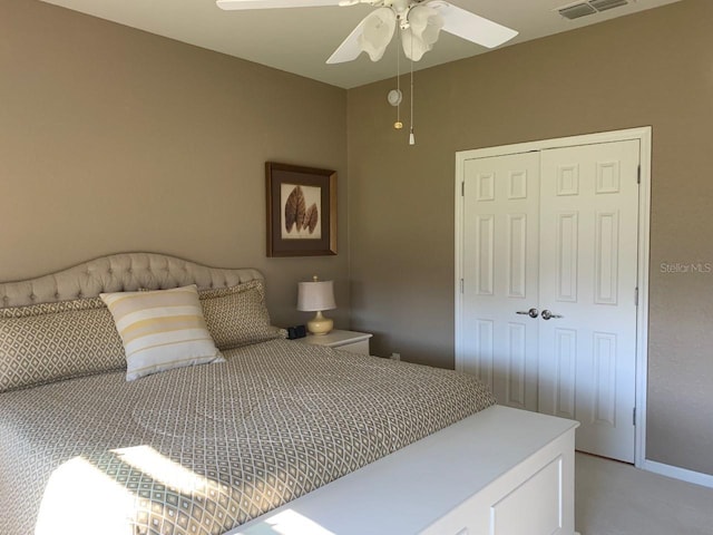 bedroom with a closet, light colored carpet, visible vents, and ceiling fan