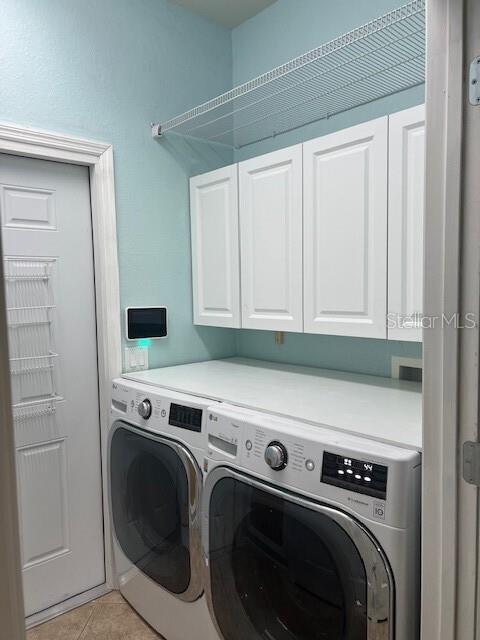 6832 SW 93rd Ave, Ocala, FL 34481 - laundry area with light tile patterned floors, cabinet space, and washer and clothes dryer